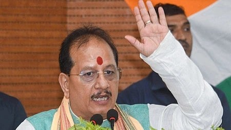 Bihar Deputy Chief Minister Vijay Kumar Sinha addressing supporters at a rally, with election banners in the background emphasising development and governance.