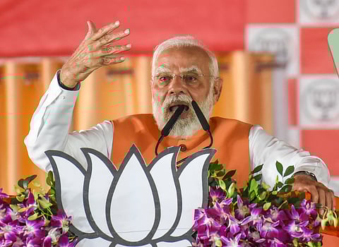 In the image PM Modi is shown adressing the people in a rally