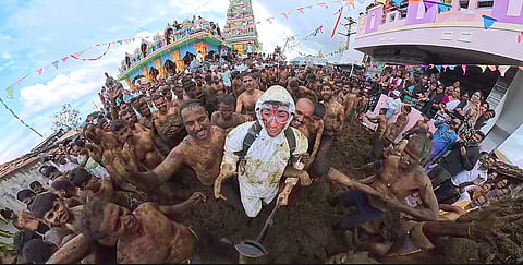 In the image American YouTuber Tyler Oliveira is shown wearing a white completely packed suit in Karnataka's cow dung festival