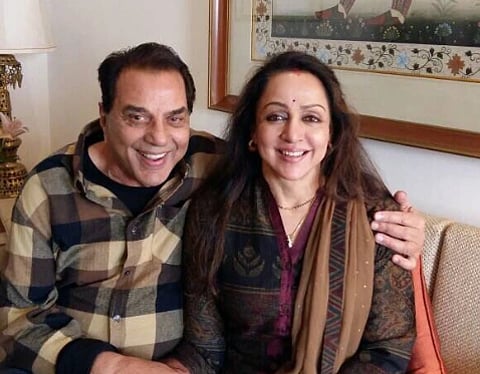 Image of Dharmendra and Hema Malini with his left arm around her shoulder.