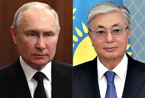 Vladimir Putin and Qasym-Zhomart Toqaev in suits. They are pictured side by side. The man on the left looks serious against a wooden backdrop, while the man on the right smiles slightly with a flag behind him.