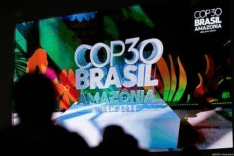 A vibrant COP30 Brasil Amazônia logo with tropical plants in the background. Silhouetted figures are in the foreground, creating an engaging, lively atmosphere.