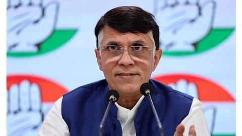 Congress leader Pawan Khera giving speech at an event. There is blurred Congress symbol of hand in the background.