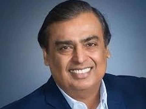 A smiling man in a dark blue suit and white shirt, set against a smooth blue gradient background. He appears friendly and confident.