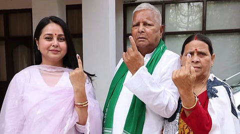 Lalu Prasad Yadav Rabri Devi and their daughter Rohini Acharya are standing, each showing an inked finger, indicating they have voted. They appear proud and serious, with a sense of civic duty.