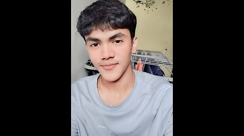 Image of 19 year old Arnav Khaire with short dark hair smiles gently at the camera, wearing a light blue shirt. The background shows a clothes rack and a light-colored wall, giving a casual, relaxed vibe.