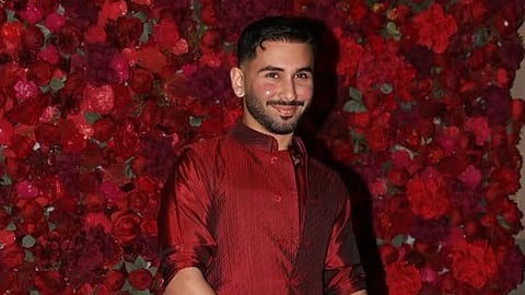 Social media influencer Orry, dressed in a red kurta, poses at an event against a backdrop of red roses that perfectly complement his outfit.