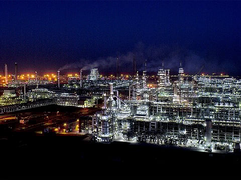 Jamnagar refinery at night, lit up at night with smoke rising from some chimneys.