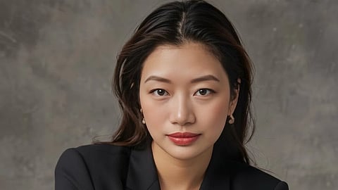 In the image a girl is shown wearing a black coat looking at the camera