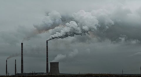 Factories emmitting gases from tall chimneys, polluting the air.