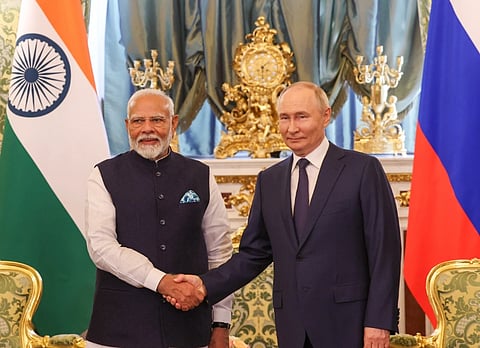 image of President Putin and PM Modi giving each other a handshake in Moscow, Russia. The Indian and Russian flags are visible in the background.