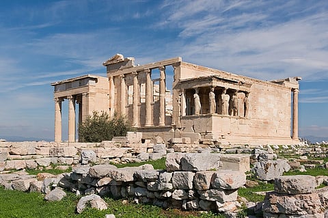 The Erechtheum, western side, Acropolis, Athens, Greece. Slighly dillapidated, sitting atop a hill, with stones piled next to the camera.