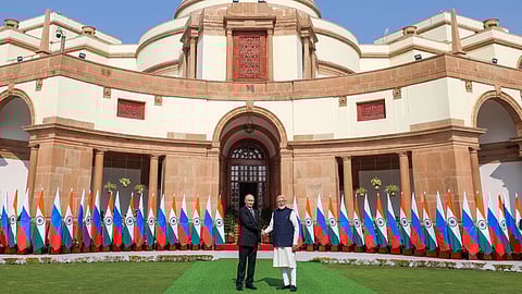 In the image Putin and Modi are shown shaking hands behind them are India and russia flags decorating the area