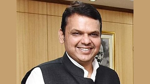 In the image CM Devendra Fadnavis is shown he is smiling at the camera wearing formal dress