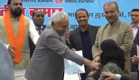 Image of Nitish Kumar pulling a Woman's hijab at a government event.