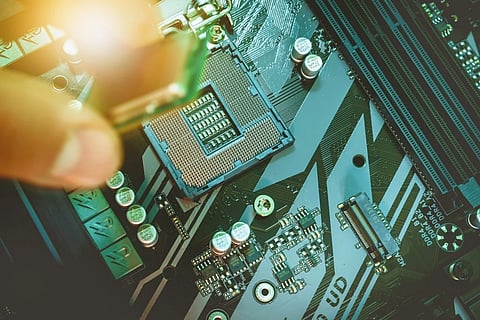 A close up of a CPU, with a hand moving to place a component on the board.