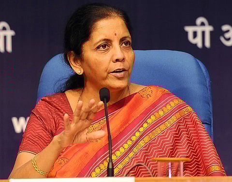 Finance Minister Nirmala Sitharaman is addressing a press conference, in an orange saree.