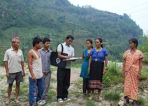 A government official collecting details from people for the 2011 census at Parengaon, Near Rinchengpong, West Sikkim. There are mountains in the background.
