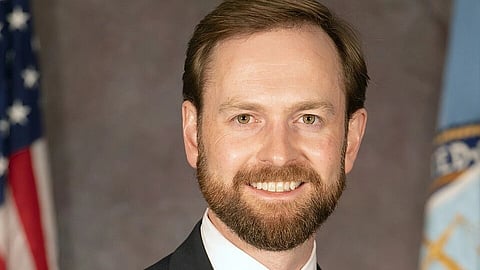 In the image Andrew Ferguson is shown wearing coat and shirt with pink tie