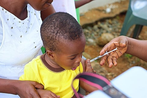 A young boy from ghana taking an injection in the upper arm.