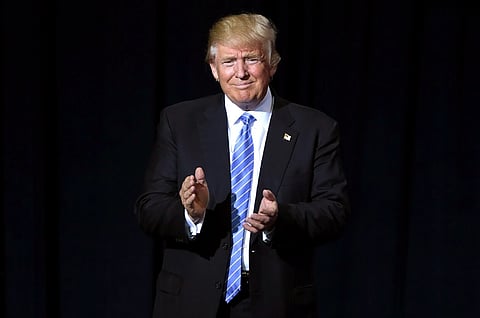 Image of Trump clapping. the background is dark. he is speaking to supporters at an immigration policy speech at the Phoenix Convention Center in Phoenix, Arizona.