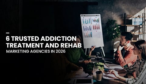 A group of people sit around a table in a dimly lit room, discussing charts on a flip board. Text overlay reads: "6 Trusted Addiction Treatment and Rehab Marketing Agencies in 2026." The atmosphere is focused and collaborative.