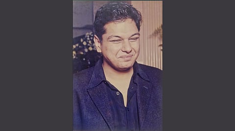 Vedanta Group chairman's son Agnivesh Agrawal smiling warmly with his eyes closed. He is wearing a dark blazer and shirt, set against a blurred background with soft lighting