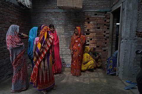 Women standing together in a small room with sunlight coming down from above in Muzaffarpur.