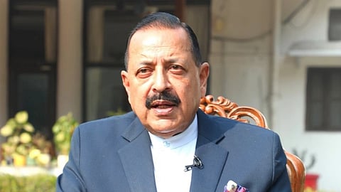 Union Minister Jitendra Singh in a blue suit sits on an ornate chair outdoors, gesturing with one hand
