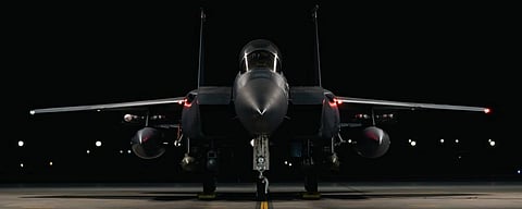 Front view of a parked jet fighter at night on a runway. Its sleek design and sharp angles are highlighted by dim lights, creating a dramatic and powerful tone.