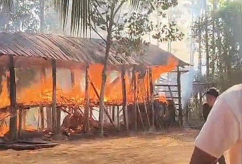 A screenshot of a video showing a hut being burned.