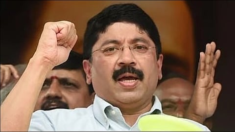 DMK MP Dayanidhi Maran wearing glasses, passionately speaking with a raised fist. Several people are in the background, adding a sense of support and solidarity.
