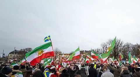 People wave the Lion and Sun flag and hold placards showing Reza Pahlavi during an anti-Iranian regime protest at Bältespännarparken in Gothenburg, Sweden on January 17, 2026.