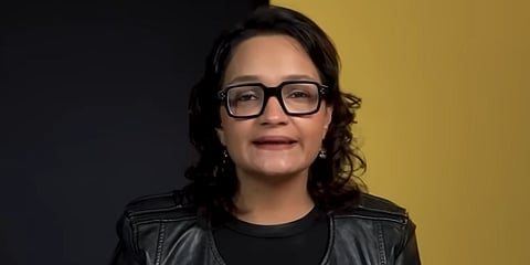 A person with glasses and a leather jacket speaks against a split black and yellow background, conveying confidence and focus.