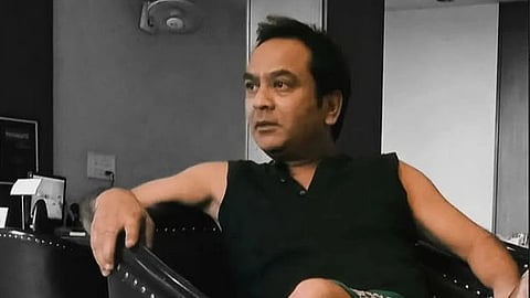 Nadeem Khan from a social media photo sitting in a vhair looking to the side in a sleeveless shirt.