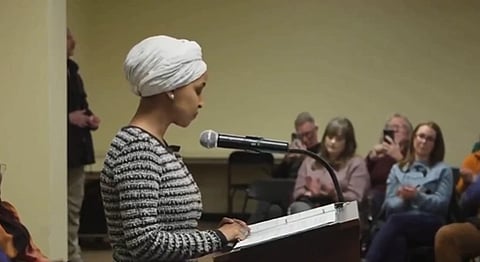In the image Ilham Omar is shown adressing the audience she is wearing a turban