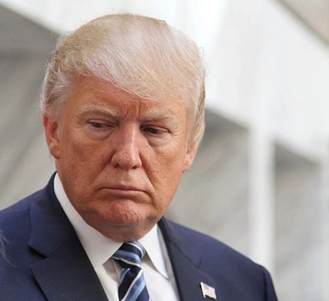 Image of Donald TrumptakenBy Gedalia Vera. in the image Trump is wearing American flag on his chest and he is looking downward.