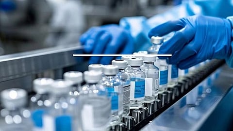 Blue-gloved hands handle glass vials on a manufacturing line, indicating a sterile laboratory environment. The scene conveys precision and professionalism.