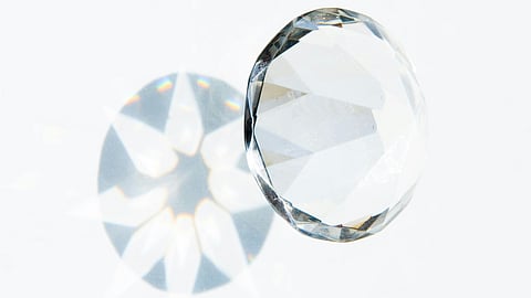 A faceted crystal ball rests on a light surface, casting a kaleidoscope of colorful reflections. The image conveys elegance and sparkle.