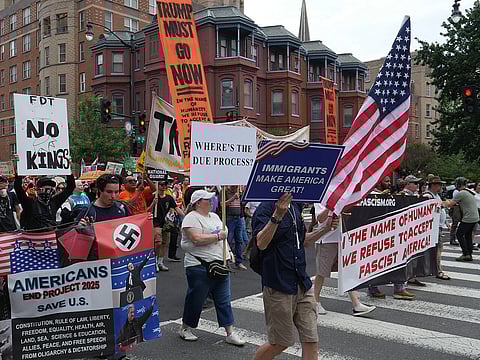 Many protesters march against Trump and ICE detentions holding banners.