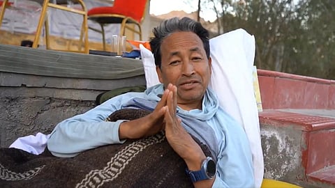 Sonam Wangchuk lying down with folded hands wearing a blanket.