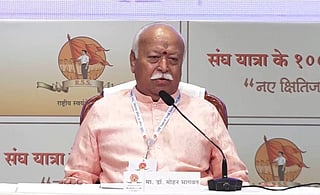 In the image RSS Chief Mohan Bhagwan is show adressing people behind him is the backdrop of RSS