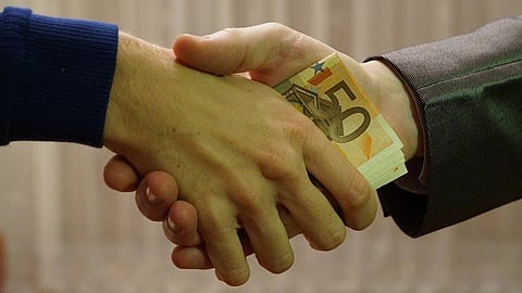 Shaking hands with euro banknotes hidden in the hands.