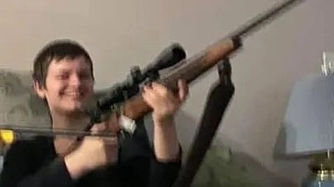 In the image the suspect Jesse van is holding a long gun and smiling in the camera