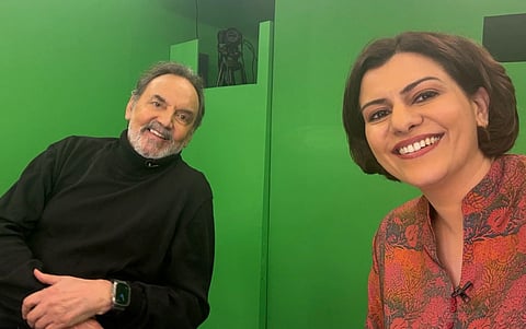 Image of Prannoy Roy (left) and Nidhi razdan(right) in a studio with a green screen behind them