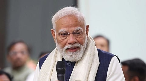PM Modi adressing a group of people he is holding a mic and is looking downwards