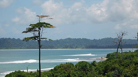 A coastal view with green islands on both sides of a blue sea with waves.