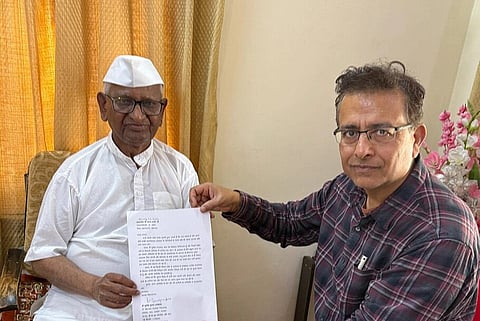 Image of Bharatiya Liberal Party (BLP) President, Dr. Munish Kumar Raizada, visiting Ralegan Siddhi, Maharashtra to meet Anna Hazare. in the image he is seen holding a paper with Anna Hazare.