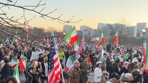 In the image a large crowd is shown with America and Iran flags