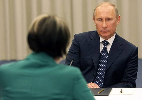 Vladimir Putin sitting across from Micheline Calmy-Rey, facing the camera